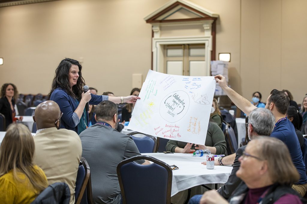 woman holding a microphone presenting poster about student success